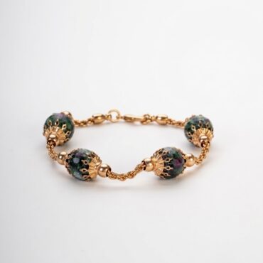 Bracciale artigianale
in lega dorata
demirouge con sfere
di pietra naturale
ruby zoisite su
sfondo bianco pulito.