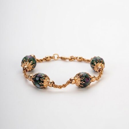 Bracciale artigianale in lega dorata demirouge con sfere di pietra naturale ruby zoisite su sfondo bianco pulito.