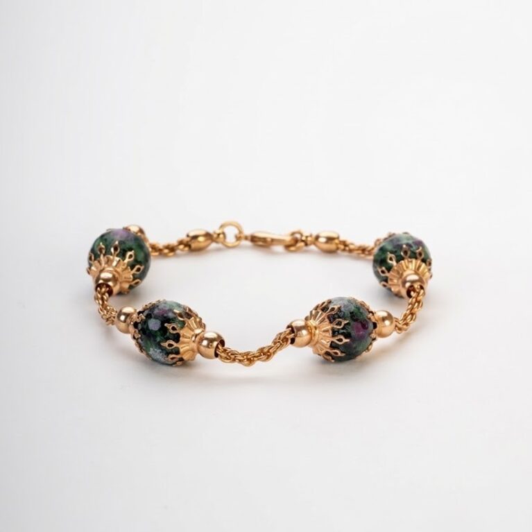 Bracciale artigianale in lega dorata demirouge con sfere di pietra naturale ruby zoisite su sfondo bianco pulito.