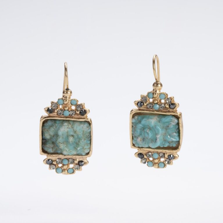 Primo piano di orecchini pendenti "Gioielli d'Autore" su sfondo bianco. I gioielli presentano un medaglione color turchese con una rosa scolpita al centro, incorniciato da cristalli europei color grigio fumo e piccoli turchesi. La finitura in oro 14 KT risplende sulla lega "Demirouge", mettendo in risalto il design artigianale unico.