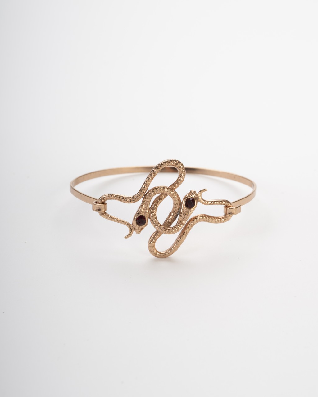 Bracciale rigido dorato con due serpenti intrecciati e occhi di pietre rosse punto luce