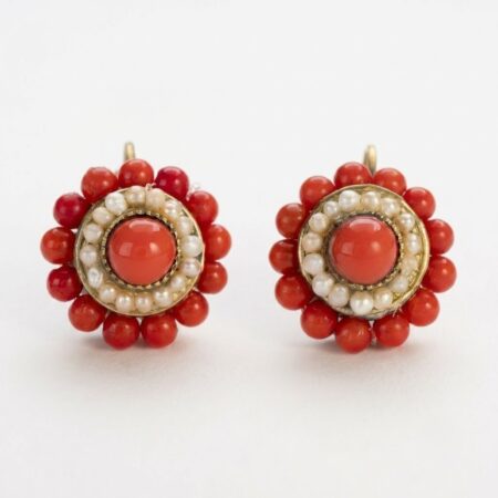 Coppia di orecchini stile borbonico con cabochon centrale rosso corallo e corona di perle di fiume su fondo chiaro