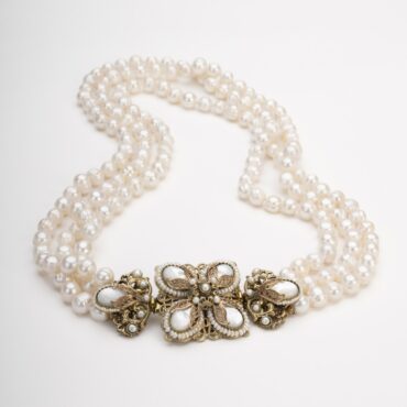 Collana di perle d'acqua dolce a tre fili. Gioiello borbonico scomponibile su sfondo bianco.