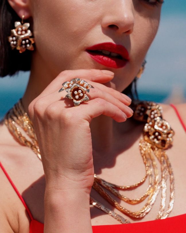 Anello Tripudio di Gigli in lega demirouge dorata indossato da una modella con rossetto rosso e gioielli barocchi coordinati Riflessi di un tempo