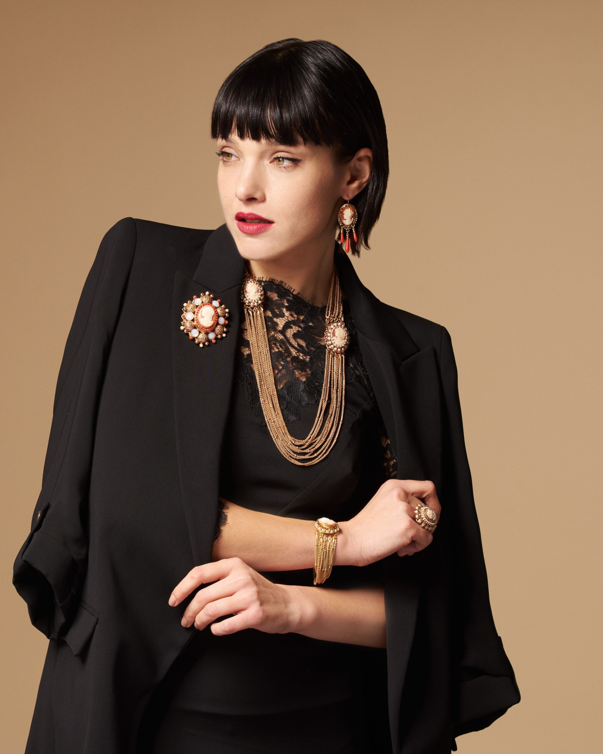 Modella con giacca nera elegante e pizzo che indossa un bracciale con cammeo e parure coordinata stile d'epoca.