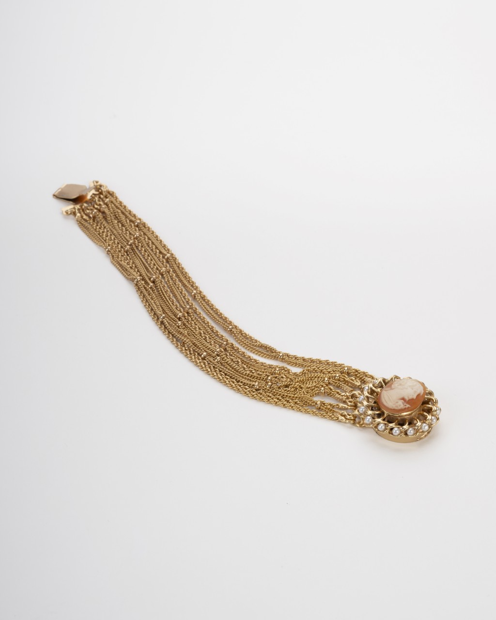 Bracciale multifilo dorato con cammeo centrale inciso a mano raffigurante un profilo classico circondato da perline su sfondo neutro.