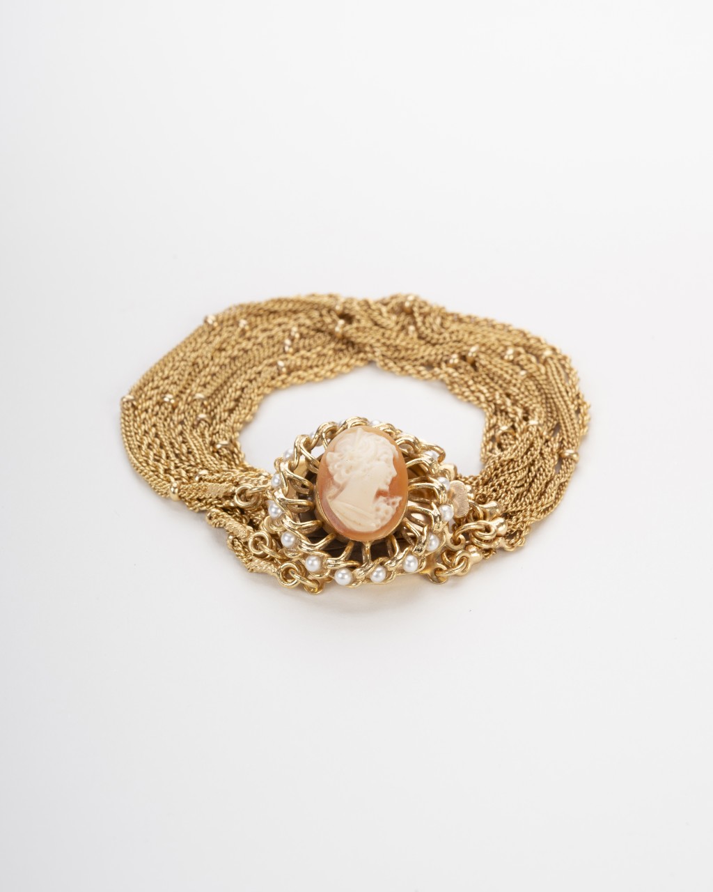 Bracciale multifilo dorato con cammeo centrale inciso a mano raffigurante un profilo classico circondato da perline su sfondo neutro.