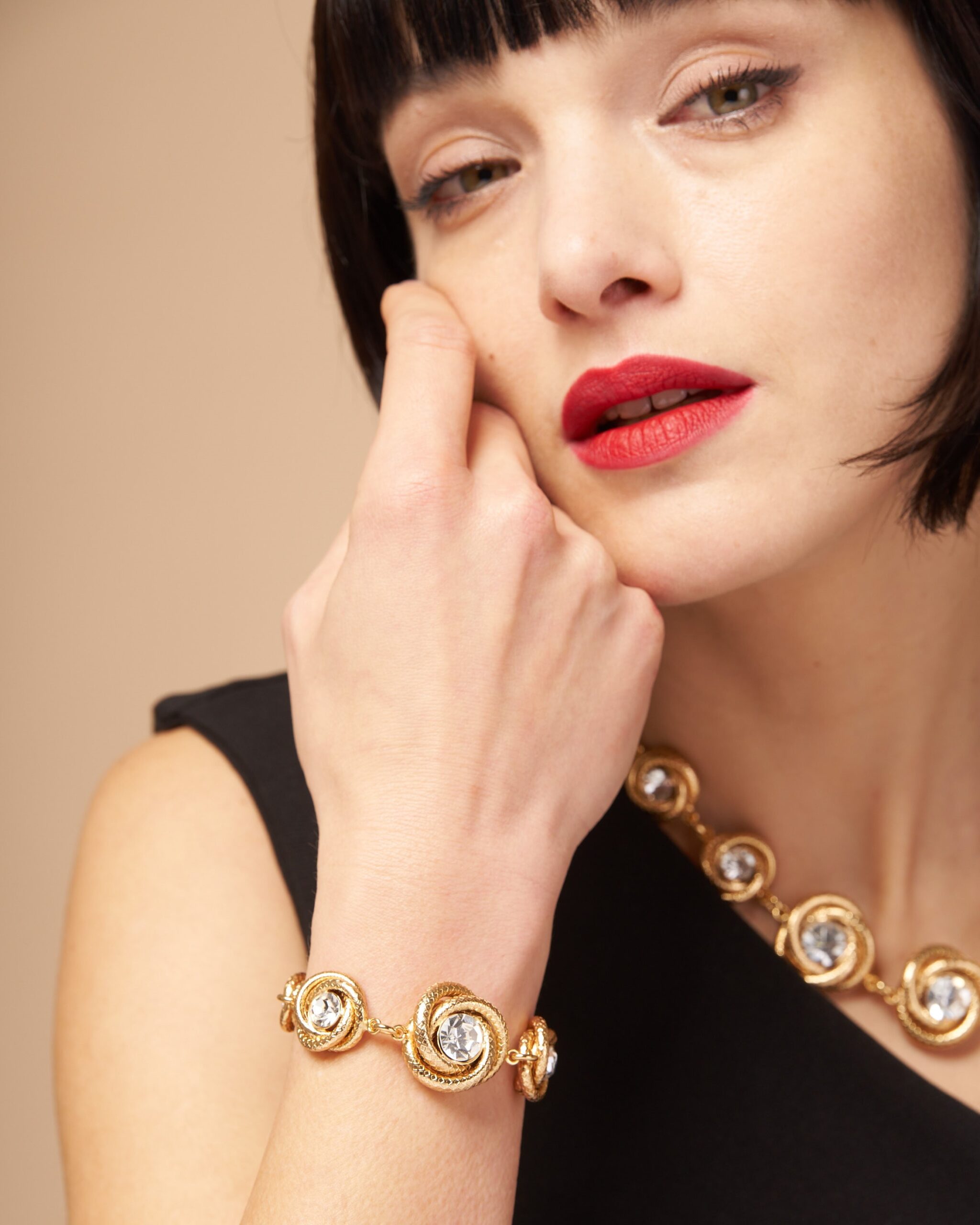 Bracciale e collana a torchon dorati indossati da modella su abito nero