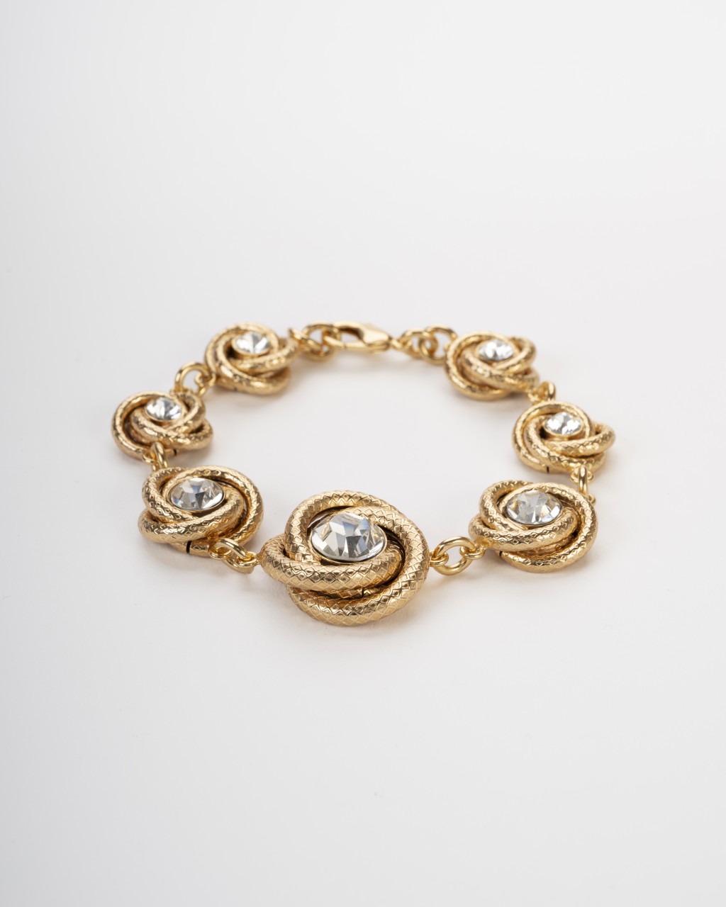 Bracciale a torchon dorato con castoni di cristallo brillante su fondo chiaro