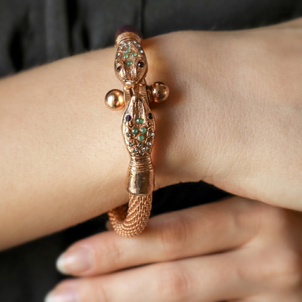 Bracciale avvolgente serpente indossato al polso con cristalli verde smeraldo e dettagli rossi