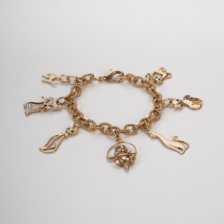 Bracciale con charms gatti e cristalli colorati steso su sfondo chiaro