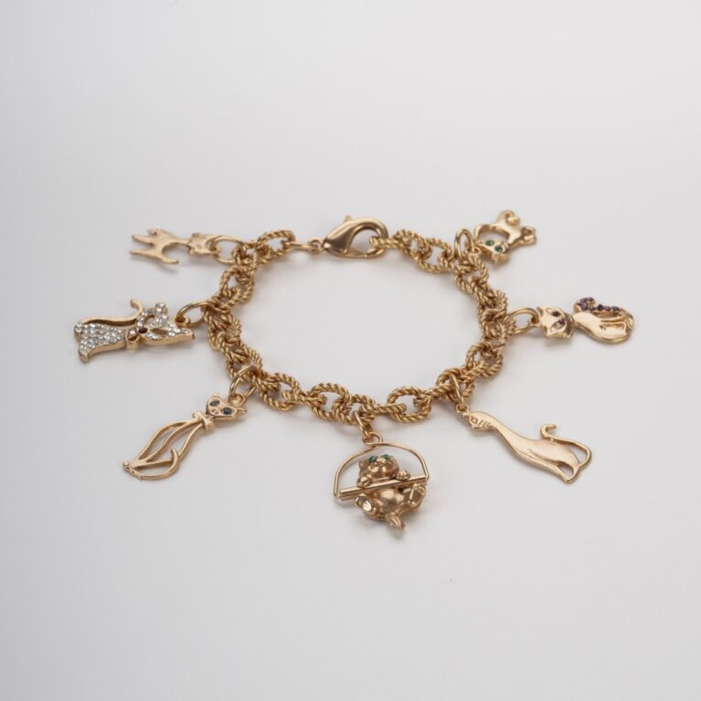 Bracciale con charms gatti e cristalli colorati steso su sfondo chiaro