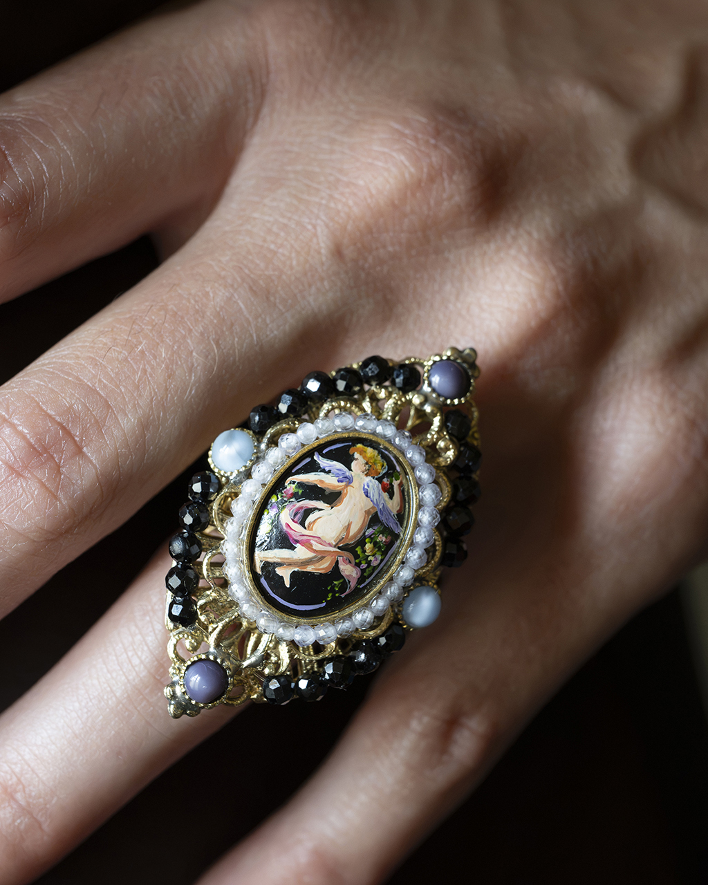 Anello con miniatura di angelo e amorino pompeiano indossato sul dito di una mano
