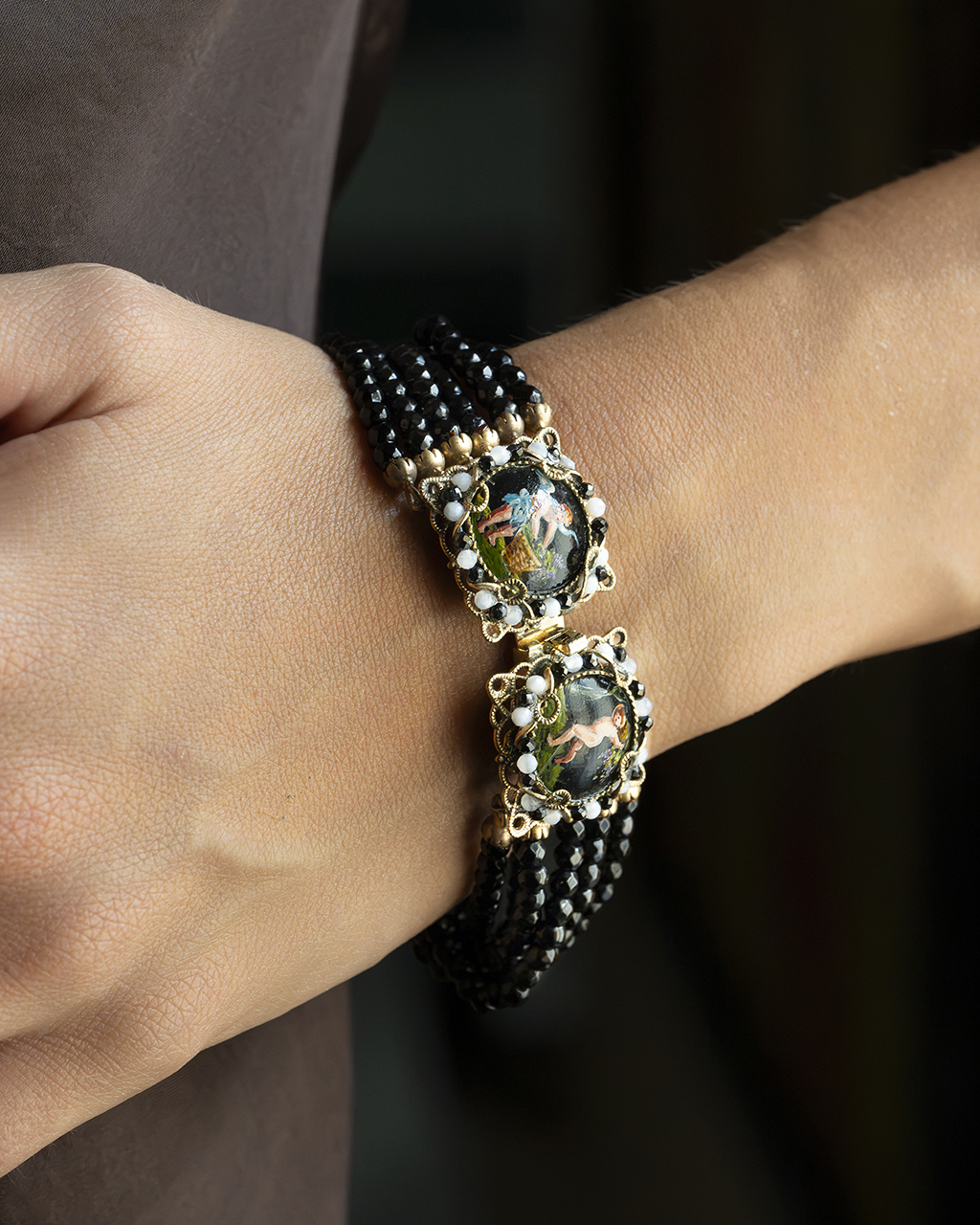 Particolare bracciale con miniature pompeiane firmate e sfaccettature in onice nera sul polso